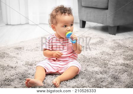 Cute little African American baby with nibbler on carpet