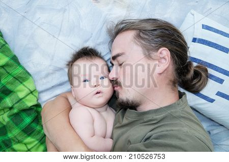 Tired sleeping father and baby girl portrait lying on bed together happy family