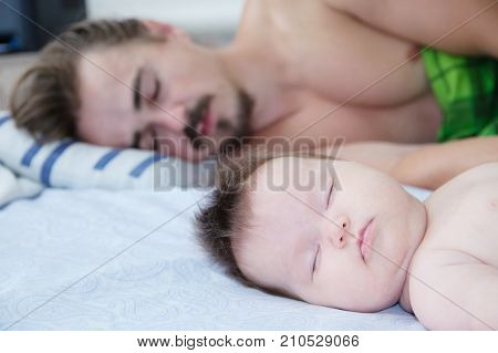 sleeping parent and baby in the morning lying on bed together happy family
