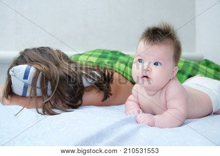sleeping parent and baby waking up in the morning lying on bed together happy family