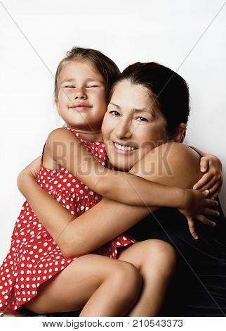 Affectionate grandmother and her cute little granddaughter smile at the camera