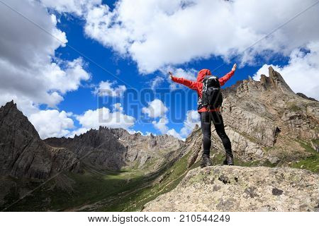 cheering woman with backpack hiking in mountains