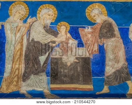 The presentation in the temple Simeon holds baby Jesus and Joseph come with two sacrificial doves in a cloth a romanesque wall-painting in Bjaresjo church Sweden November 6 2009