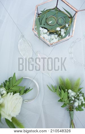 Fancy wedding details on a table with some greenery. Eustoma and eucalyptus. Wedding rings in a fancy box. Some jewerly