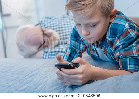 Little Boy Using Smartphone On Bed