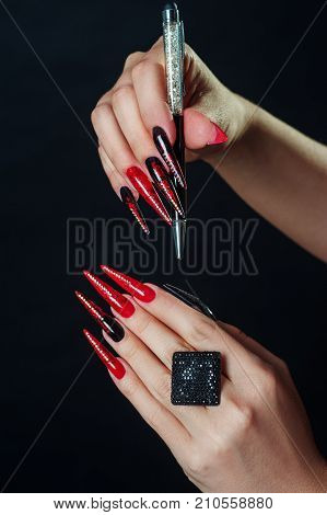 Holiday halloween or new year nail art design ideas. Beauty Fashion Hands Trendy Stylish Colorful manicure. Black Red fingers with rhinestones nailpolish isolated on black. Glamour and scary concept