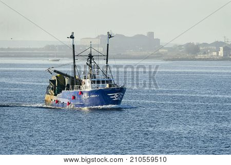 New Bedford Massachusetts USA - October 23 2017: Fishing vessel Luso American I entering New Bedford harbor on foggy morning with Fort Taber in background