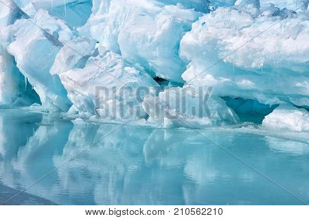 Blue growler piece of iceberg with reflection in calm water. Global warming, melting of ice. Arctic ocean