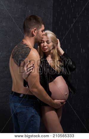 Beautiful pregnant couple in love on the background. Hands of husband on the tummy of his pregnant wife. Young man tenderly stroked pregnant belly of his wife. Husband kissing pregnant belly.