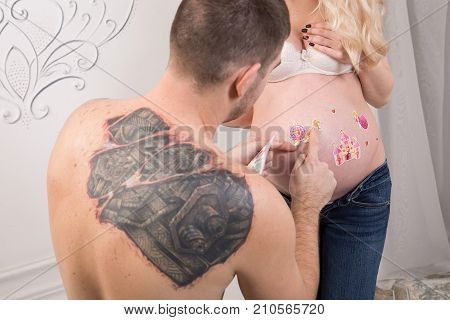 Beautiful pregnant couple in love on the background. Hands of husband on the tummy of his pregnant wife. Young man tenderly stroked pregnant belly of his wife. Husband kissing pregnant belly.