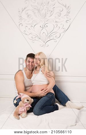 Beautiful pregnant couple in love on the background. Hands of husband on the tummy of his pregnant wife. Young man tenderly stroked pregnant belly of his wife. Husband kissing pregnant belly.