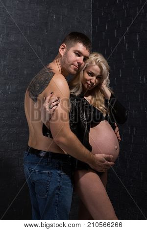 Beautiful pregnant couple in love on the background. Hands of husband on the tummy of his pregnant wife. Young man tenderly stroked pregnant belly of his wife. Husband kissing pregnant belly.