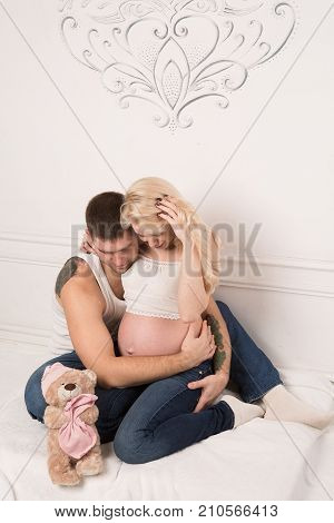 Beautiful pregnant couple in love on the background. Hands of husband on the tummy of his pregnant wife. Young man tenderly stroked pregnant belly of his wife. Husband kissing pregnant belly.