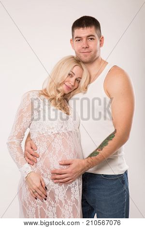 Beautiful pregnant couple in love on the background. Hands of husband on the tummy of his pregnant wife. Young man tenderly stroked pregnant belly of his wife. Husband kissing pregnant belly.