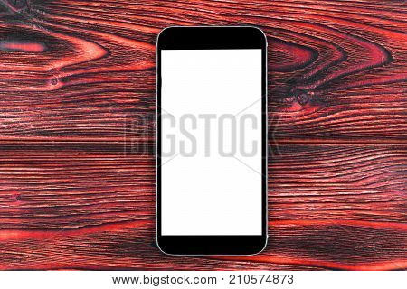 Mobile phone with blank screen mock up. isolated white screen on red wooden table background. Smartphone on wooden table. Smartfone white screen
