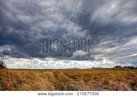 Dramatic Landscape with storm clouds in the sky on a field with dry grass