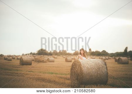 Beautiful Girl In A Field With A Bales Of Hay