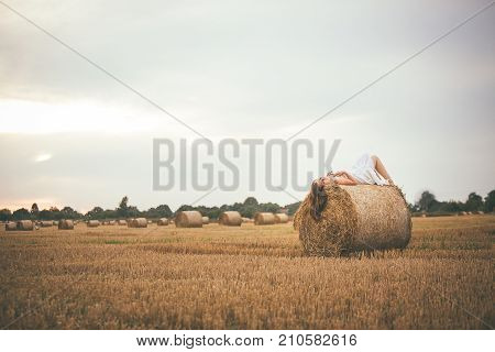 Beautiful Girl Lying On A Bale Of Hay In The Field
