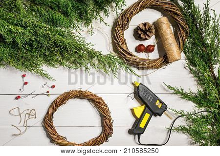 Make a Christmas wreath with your own hands. Spruce branch, Christmas wreath and gifts on a white wooden background. Workplace for preparing handmade decorations. Christmas and New year