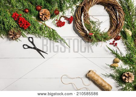 Make a Christmas wreath with your own hands. Spruce branch, Christmas wreath and gifts on a white wooden background. Workplace for preparing handmade decorations. Christmas and New year