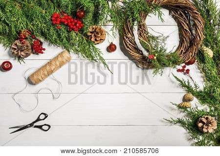 Make a Christmas wreath with your own hands. Spruce branch, Christmas wreath and gifts on a white wooden background. Workplace for preparing handmade decorations. Christmas and New year