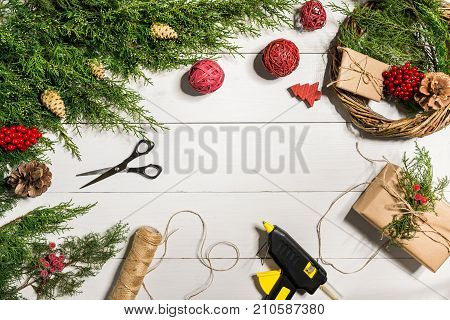 Make a Christmas wreath with your own hands. Spruce branch, Christmas wreath and gifts on a white wooden background. Workplace for preparing handmade decorations. Christmas and New year