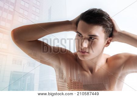Calmness. Self assured young serious man looking to the right with his hands behind his head