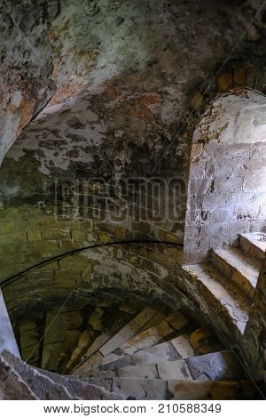 Cellar spiral steps with side window light. Looking down to the dungeon.