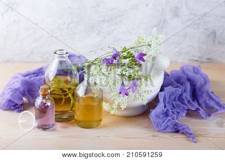 Bottles with natural aroma of essential oils mortar and wild flowers Spa concept. Herbal medicine.