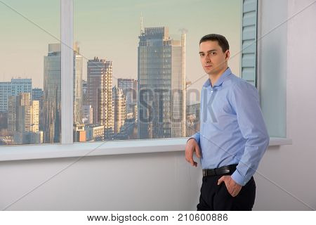Man experienced managing director dressed in luxury suit is resting after conference with his staff while is standing near office window background with copy space for your advertising text message. skyscrapers