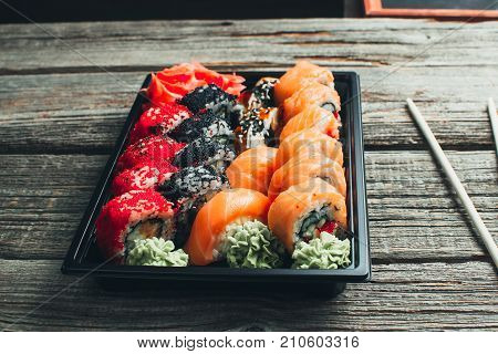 On A Wooden Table In The Black Container Are Nicely Decomposition Sushi