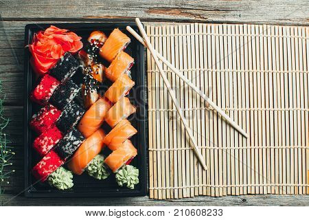 On A Wooden Table In The Black Container Are Nicely Decomposition Sushi