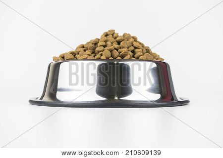 Pet food in a metal bowl on a floor.