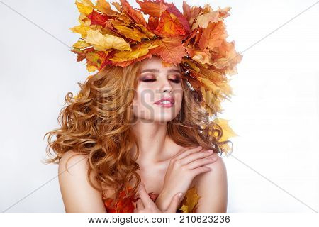 Beauty model girl with autumn bright leaves hairstyle. Beautiful Fashion female with Autumnal Make up and Hair style. Autumn woman
