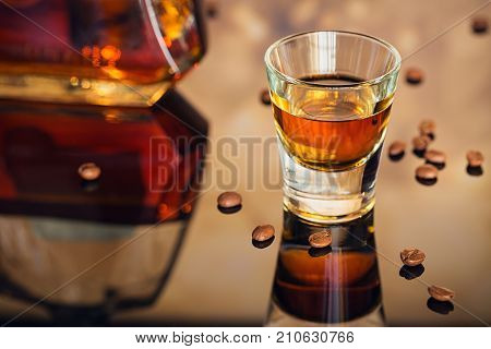 Cognac or liqueur and coffee beans on a glass table. Seasonal holidays concept.