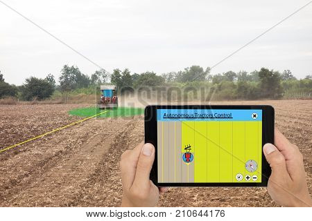 smart agriculture concept farmer use tablet to control autonomous tractor while plow the soil in field self driving tractor while working and can control the direction deep of plow