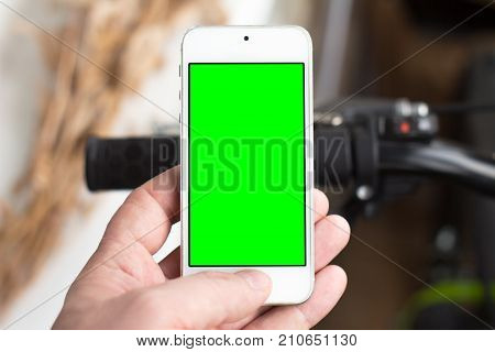 Man's hand use smartphone while he stands near by the road with bicycle. Green screen