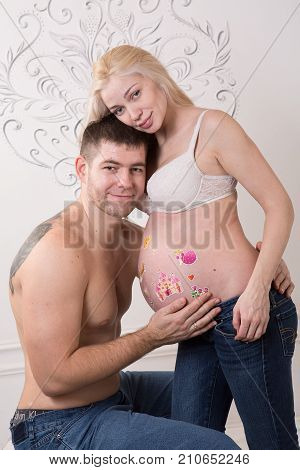Beautiful pregnant couple in love on the background. Hands of husband on the tummy of his pregnant wife. Young man tenderly stroked pregnant belly of his wife. Husband kissing pregnant belly.