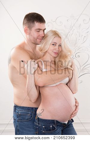 Beautiful pregnant couple in love on the background. Hands of husband on the tummy of his pregnant wife. Young man tenderly stroked pregnant belly of his wife. Husband kissing pregnant belly.