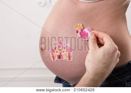 Beautiful pregnant couple in love on the background. Hands of husband on the tummy of his pregnant wife. Young man tenderly stroked pregnant belly of his wife. Husband kissing pregnant belly.