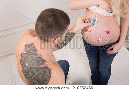 Beautiful pregnant couple in love on the background. Hands of husband on the tummy of his pregnant wife. Young man tenderly stroked pregnant belly of his wife. Husband kissing pregnant belly.