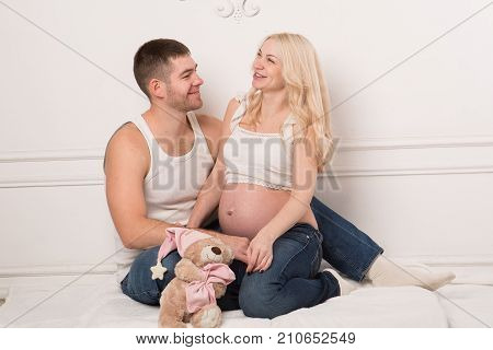 Beautiful pregnant couple in love on the background. Hands of husband on the tummy of his pregnant wife. Young man tenderly stroked pregnant belly of his wife. Husband kissing pregnant belly.