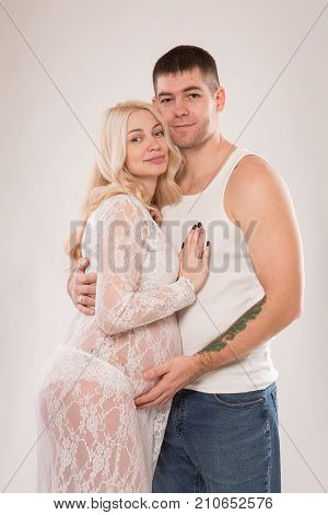 Beautiful pregnant couple in love on the background. Hands of husband on the tummy of his pregnant wife. Young man tenderly stroked pregnant belly of his wife. Husband kissing pregnant belly.