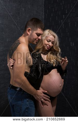 Beautiful pregnant couple in love on the background. Hands of husband on the tummy of his pregnant wife. Young man tenderly stroked pregnant belly of his wife. Husband kissing pregnant belly.