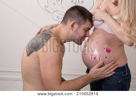 Beautiful pregnant couple in love on the background. Hands of husband on the tummy of his pregnant wife. Young man tenderly stroked pregnant belly of his wife. Husband kissing pregnant belly.