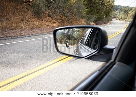 Motorcycle following a car in the side mirror