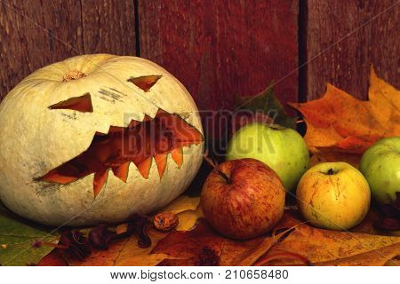 Pumpkin Halloween and apples on autumn leaves next to a wooden background
