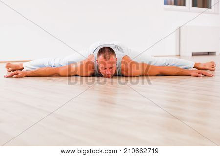 Adult man practicing yoga, Upavistha Konasana / Seated Angle Pose