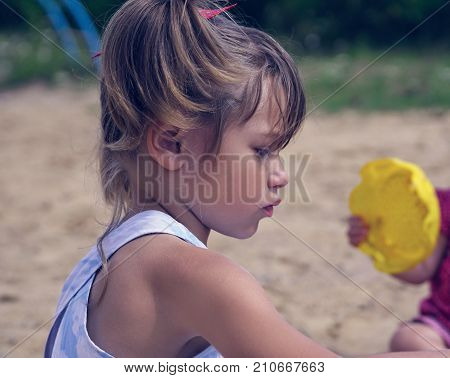 Two sisters play in the sandbox on a hot summer day. Concept of children's summer games.