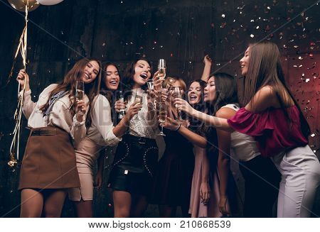 Girls make a New Year wish and drinking champagne. Happy group of attractive girls dancing with glasses of champagne